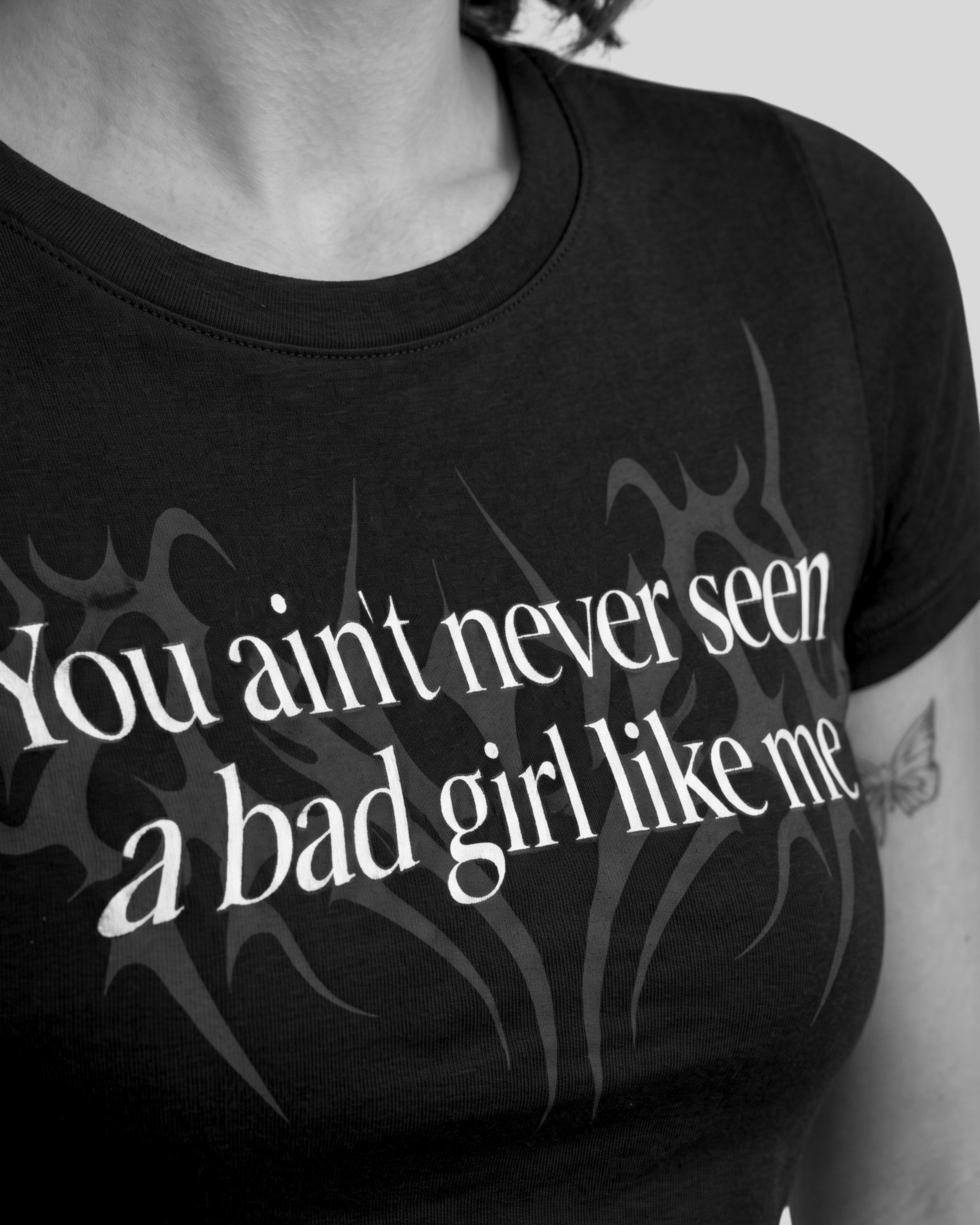 Close up of black crop top with bold bad girl quote graphic, aesthetic typography streetwear for women inspired by underground rap reble vibe and dhurandhar style design, Close up detail of aesthetic black graphic crop top with statement quote, premium gen z streetwear fabric and bold bad girl fashion design